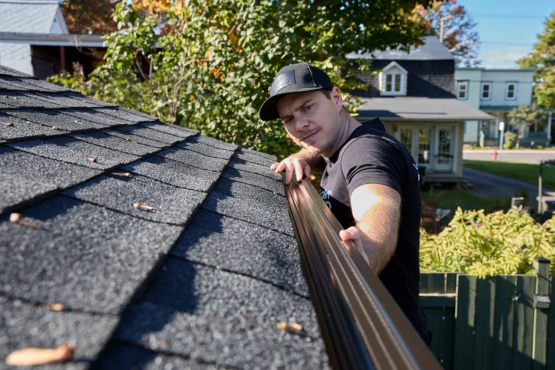 Installer carrying a new seamless gutter up a ladder
